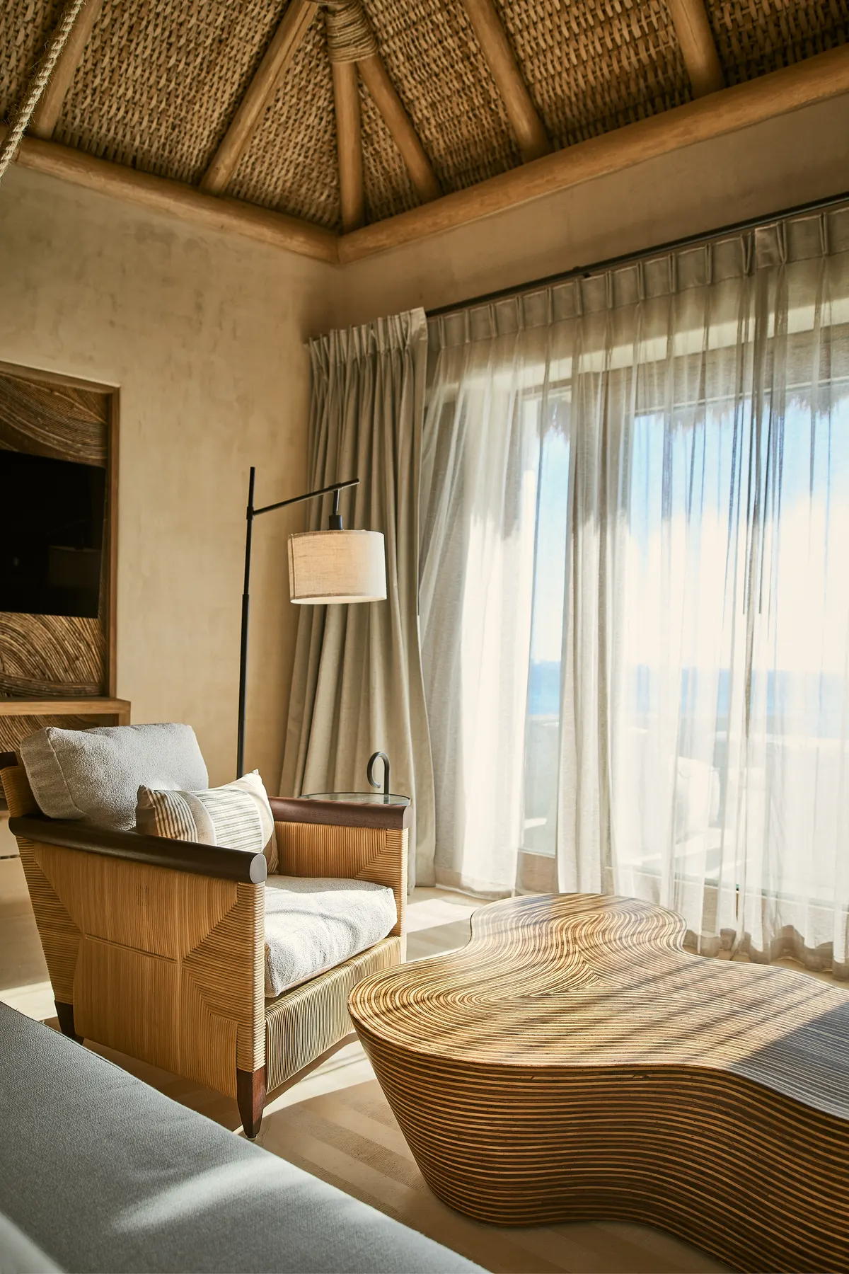 Sala de estar con sillón de ratán y mesa de centro en Villa Wayak