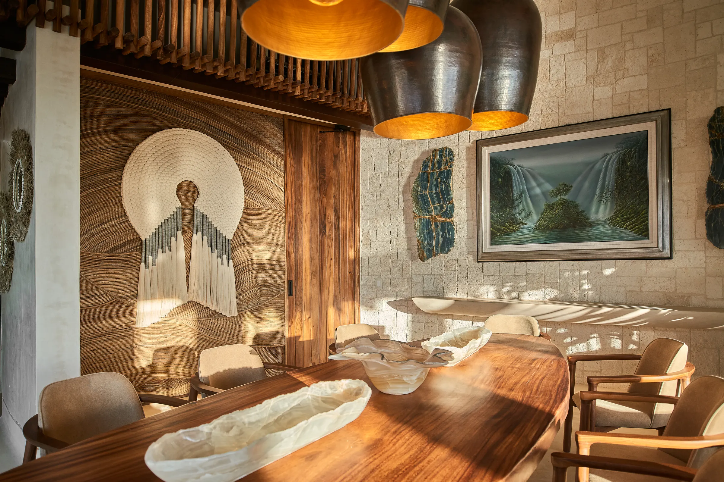 Comedor con arte tejido en la pared y candiles de latón en Villa Wayak