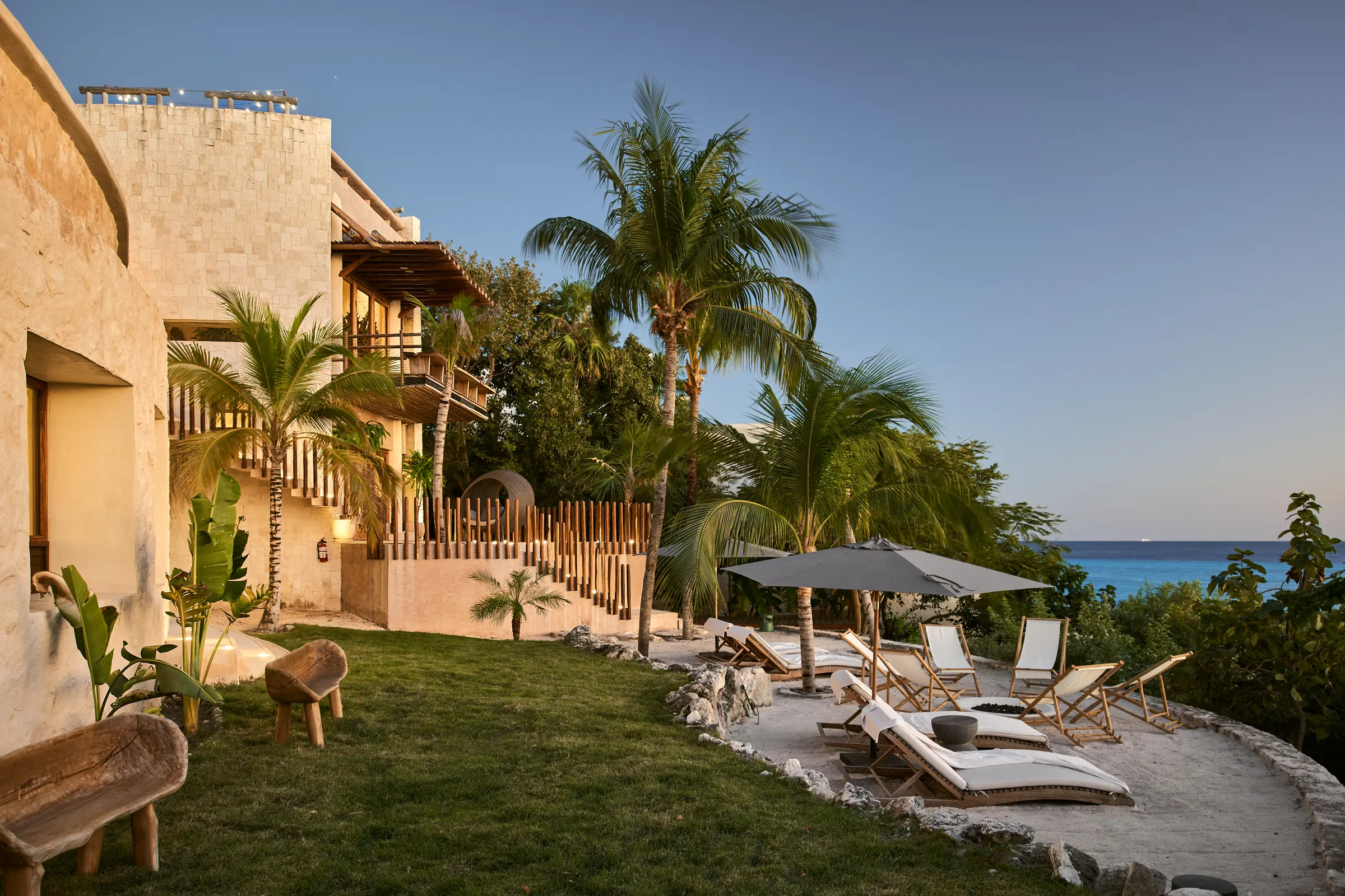 Jardín con camastros y vista al mar al atardecer en Villa Wayak